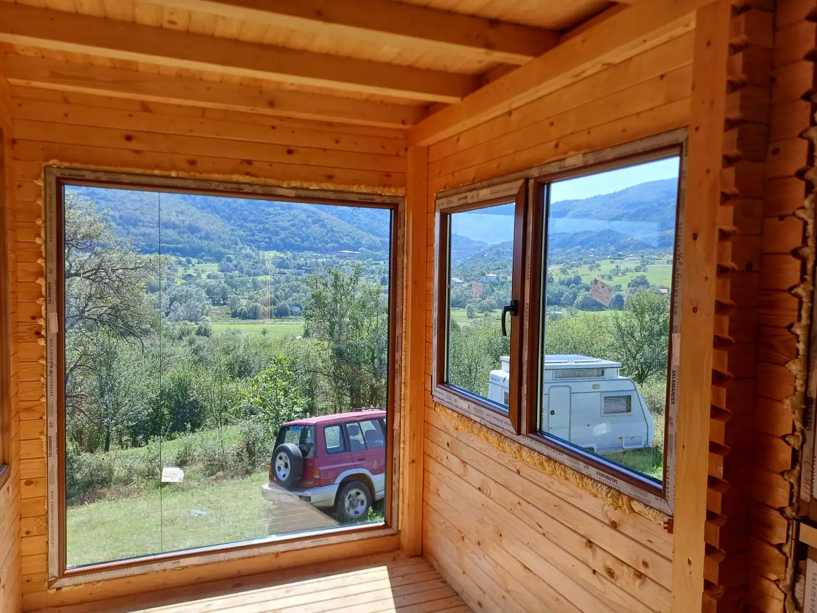 Cabană din lemn cu ferestre pe colț și vedere la munte