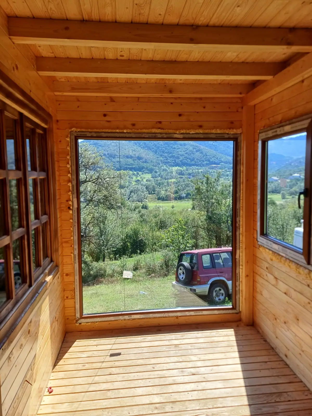 Cabană din lemn cu ferestre și vedere la munte